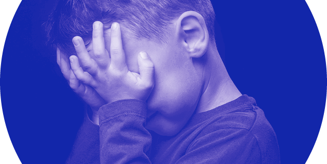 Unhappy young boy with head in hands