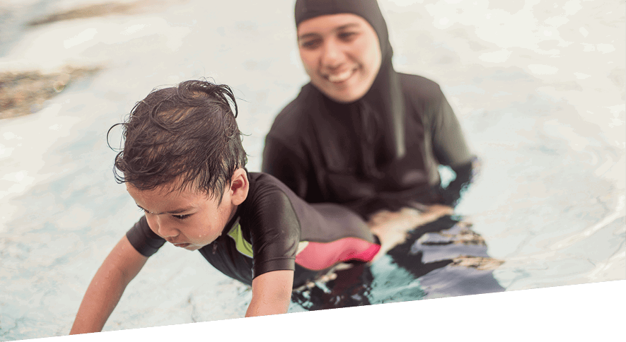 Mother helping young boy learn to swim
