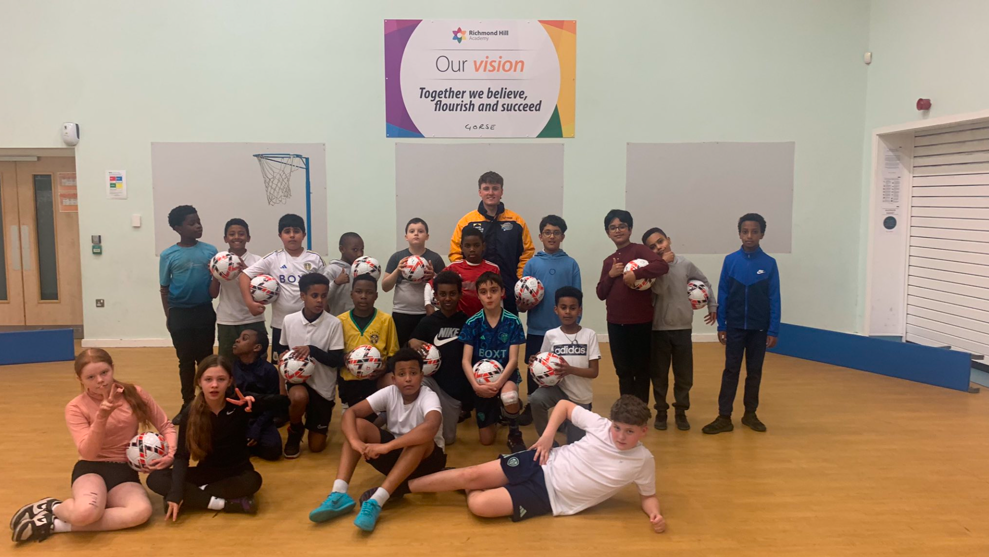 Children posing for a group photo with footballs